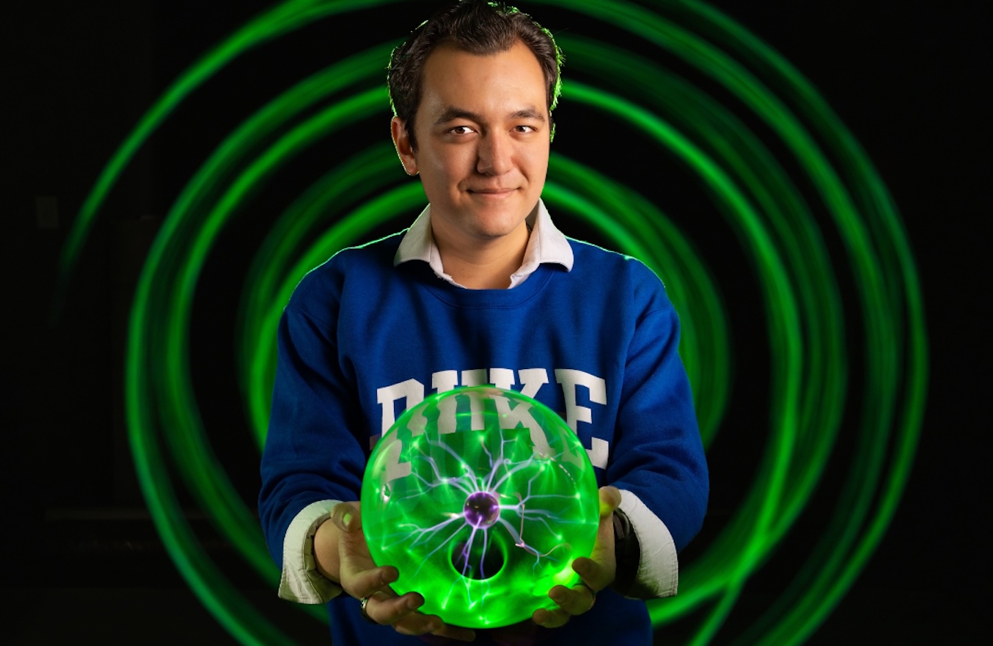 Tyler Ratcliffe holding a green plasma ball with green concentric circles in the background.
