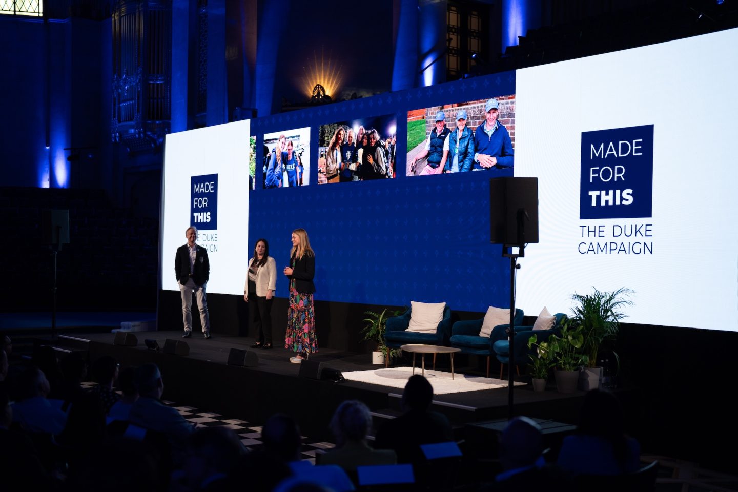 Three people standing on a stage with a blue and white MADE FOR THIS backdrop behind them.